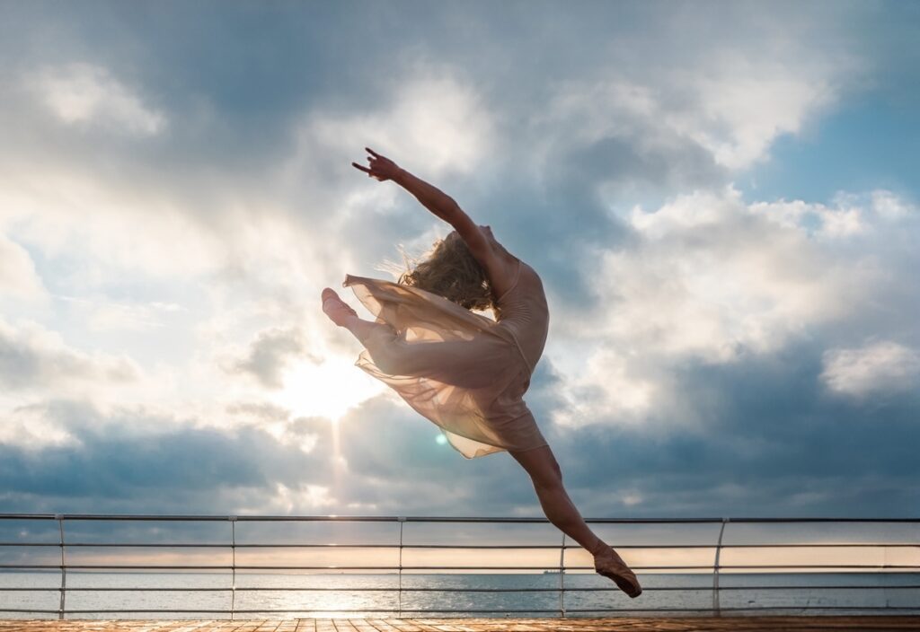 Eine Ballerina im Sprung vor dem Meer.